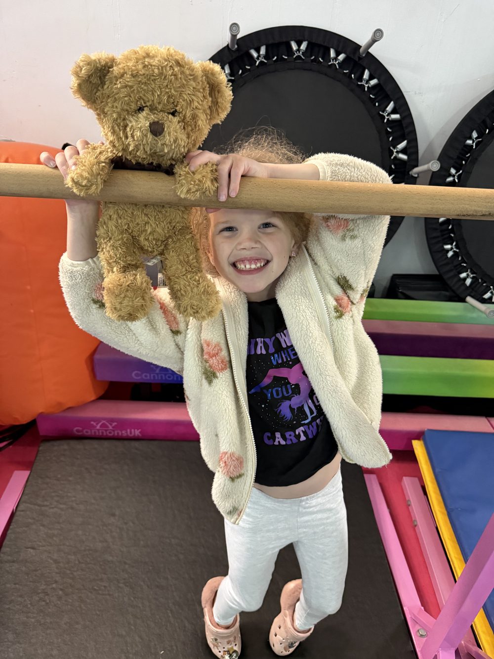 A young gymnast hanging from the bar